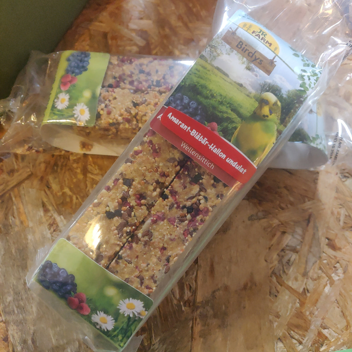 To stænger af JR Farms Fugle kracker med frugt, fra JR Farm 150g granola siddende oven på et træbord.