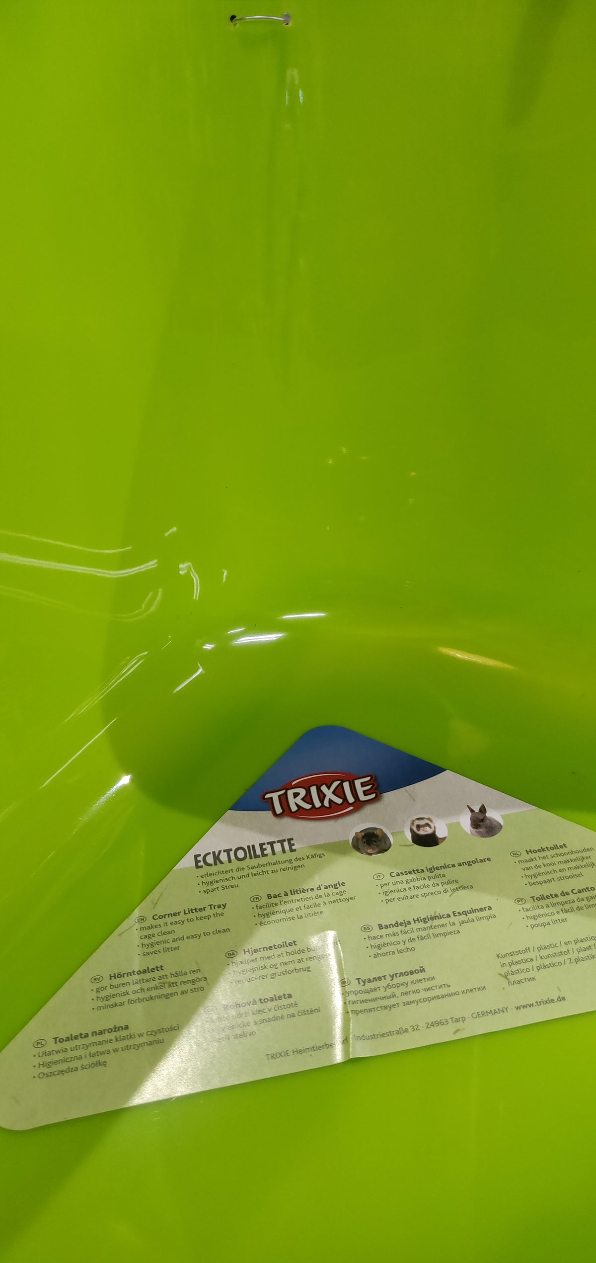 En grøn plastikbeholder med en etiket på egnet til Hjørnetoilet til kaniner, marsvin, fritter o.l. (gnavere) af Trixie.