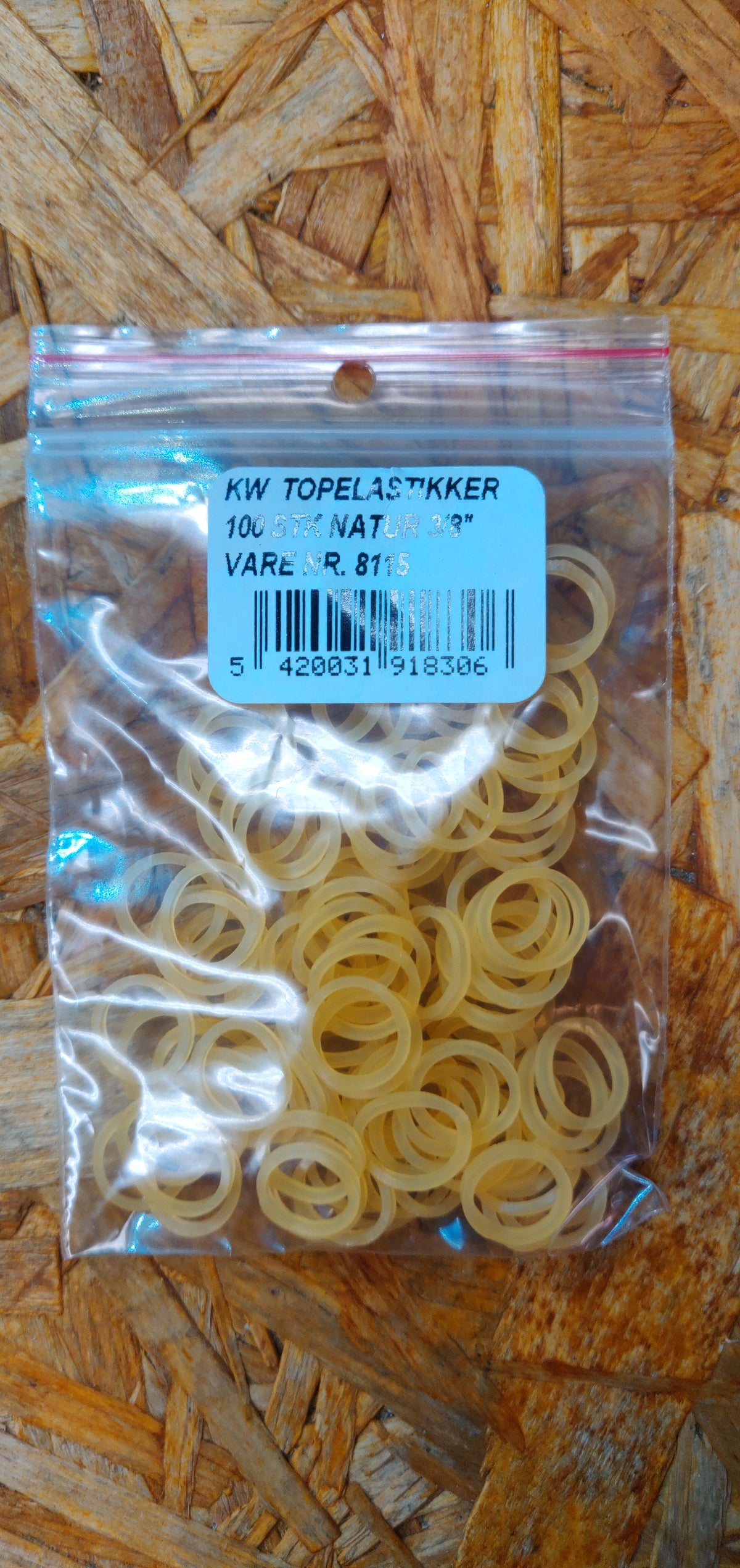 En pose Hårelastikker til hunde, forskellige farver fra Kw, siddende på en træoverflade.